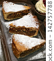 Three pieces of nut pie sprinkled with powdered sugar displayed in a bakery, showcasing fresh sweet pastries arranged attractively for customers on the counter 142757788