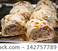 Meringue roll with a sweet filling is displayed in a confectionery shop, showcasing a delicate baked meringue dessert with an appealing layered appearance 142757789