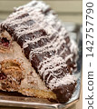 Chocolate coated pastries with coconut flakes are arranged in a confectionery display, offering an appealing combination of rich chocolate coating and delicate coconut decoration 142757790