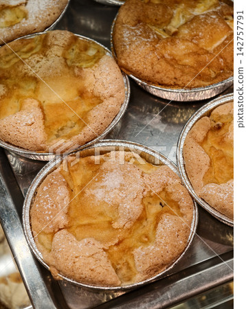 Round apple pies placed in foil dishes are arranged in a confectionery display, creating a neat presentation of sweet pastries with a delicious apple filling Round apple pies placed in foil dishes are arranged in a confectionery display, creating a neat presentation of sweet pastries with a delicious apple filling 142757791