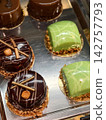 Pastries are neatly arranged in a supermarket display case, presenting sweet baked desserts in an appealing retail setting for shoppers 142757793