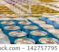 Blue and yellow cans of fizzy beverages grouped in packaging inside a warehouse, showing a substantial supply of packaged carbonated drinks in storage 142757795
