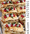 Baked lasagna covered with white cheese pieces, sliced small red tomatoes and fresh dill, highlighting the rich texture and colorful topping of the dish 142757801