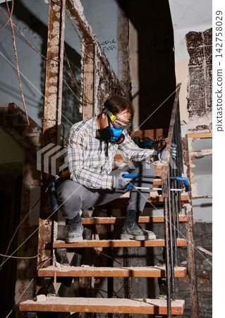 Salvage expert meticulously disassembles decommissioned stairs Salvage expert meticulously disassembles decommissioned stairs 142758029