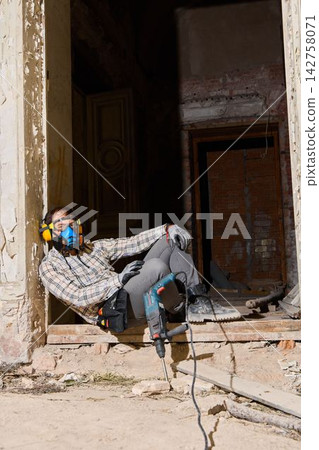 Worker leans against door frame after completing project Worker leans against door frame after completing project 142758071