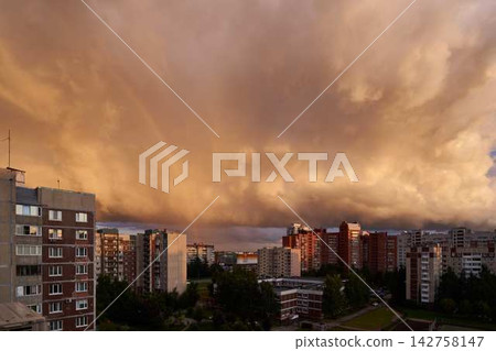 Sunlit apartment blocks glow under dramatic orange sky with rainbow over residential towers at golden sunset over urban horizon, rooftops and quiet streets with silhouetted windows 142758147