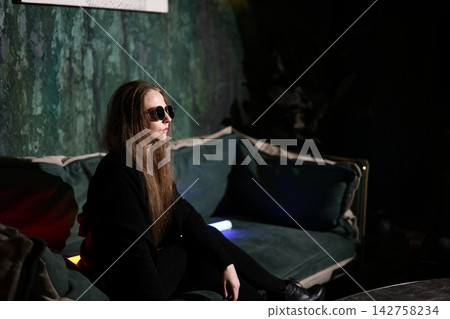 Relaxed woman enjoying her time on colorful sofa with shades Relaxed woman enjoying her time on colorful sofa with shades 142758234