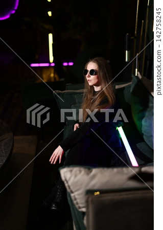 Atmospheric scene of woman lounging in vibrant purple illuminated space Atmospheric scene of woman lounging in vibrant purple illuminated space 142758245