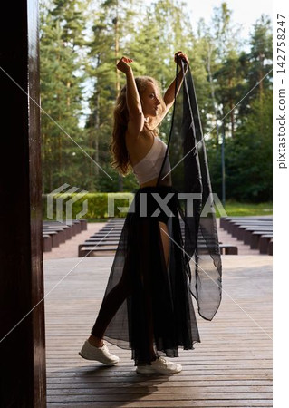 Elegant performer lifts dress in peaceful forest setting Elegant performer lifts dress in peaceful forest setting 142758247
