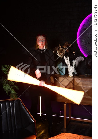 Woman standing beside luminous neon artwork in simple surroundings Woman standing beside luminous neon artwork in simple surroundings 142758248