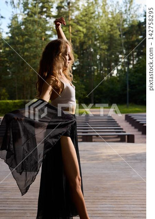 An expressive dancer strides confidently amid sunlight and trees 142758295