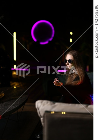 Woman relaxing at bar with luminous drink and reflective feelings Woman relaxing at bar with luminous drink and reflective feelings 142758296