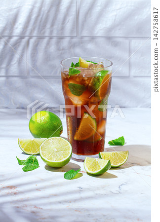 Refreshing soft drink, with cola, lime and mint, on a marble surface, sunlight, no people, Refreshing soft drink, with cola, lime and mint, on a marble surface, sunlight, no people, 142758617