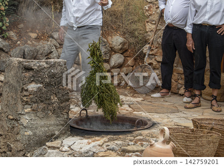 Traditional preparation of escalda process with herbs in boiling copper kettle for drying raisins in Spain Traditional preparation of escalda process with herbs in boiling copper kettle for drying raisins in Spain 142759201
