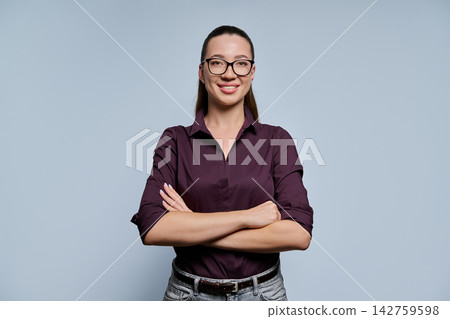 Confident businesswoman in eyeglasses standing with arms crossed studio shot Confident businesswoman in eyeglasses standing with arms crossed studio shot 142759598