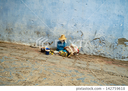 beggar sitting beside blue painted wall beggar sitting beside blue painted wall 142759618