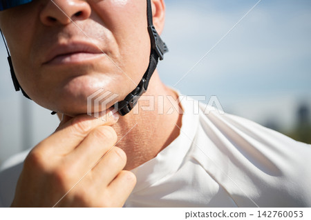 Male cyclist fastening safety helmet strap close up 142760053