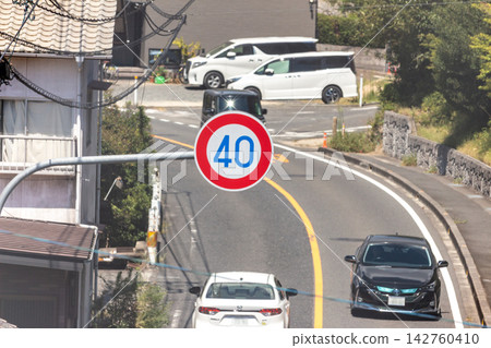 從高角度俯瞰一條住宅街道，可以看到一輛汽車正在彎道上行駛，路邊有一個限速 40 公里/小時的標誌。 142760410