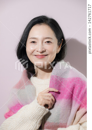 一張明亮的冬日照片，一位五十多歲的女性身披披肩，面帶自然微笑，展現出迷人的美麗。 142761717
