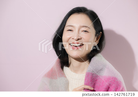 一張明亮的冬日照片,一位五十多歲的女性身披披肩,面帶自然微笑,展現出迷人的美麗。 一張明亮的冬日照片,一位五十多歲的女性身披披肩,面帶自然微笑,展現出迷人的美麗。 142761719