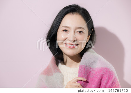 一張明亮的冬日照片,一位五十多歲的女性身披披肩,面帶自然微笑,展現出迷人的美麗。 一張明亮的冬日照片,一位五十多歲的女性身披披肩,面帶自然微笑,展現出迷人的美麗。 142761720