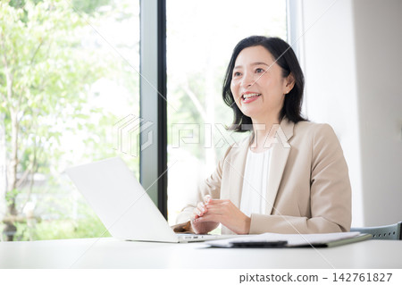 一位五十多歲的女性面帶微笑地與客戶面對面諮詢；一位女商人正在辦公室裡進行解釋和提出建議；溝通。 142761827