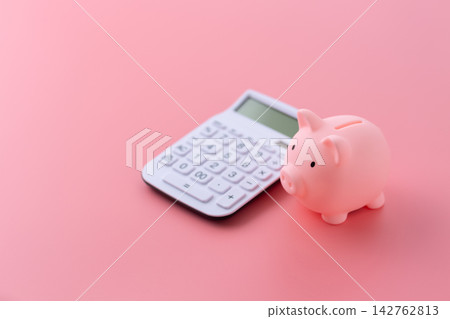 粉紅色背景上的小豬存錢筒和白色計算器。 142762813