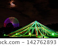 一座燈火輝煌的摩天輪和璀璨的夜景在夜空映襯下閃閃發光。 142762893
