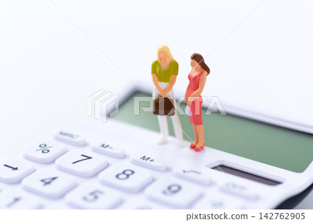 白色背景上的一個年輕女子玩偶和一個白色計算器。 白色背景上的一個年輕女子玩偶和一個白色計算器。 142762905