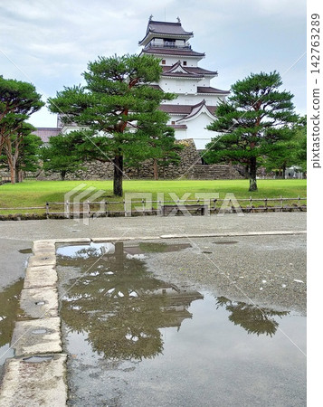 Aizu-Wakamatsu Castle reflected in puddles after the rain. 142763289