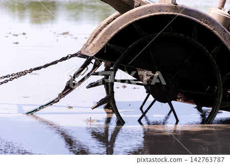 Paddle wheel aerator operating shallow aquaculture pond water showing mechanical equipment used for oxygenation circulation fish farming management Paddle wheel aerator operating shallow aquaculture pond water showing mechanical equipment used for oxygenation circulation fish farming management 142763787