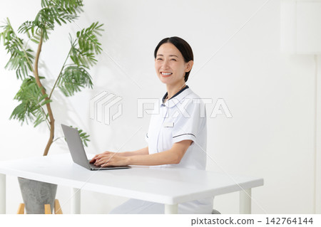 A woman in a white coat operating a computer. A woman in a white coat operating a computer. 142764144