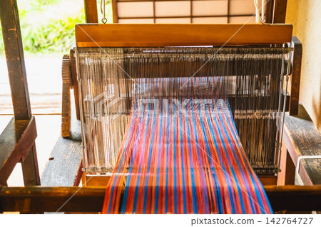 Traditional wooden looms and vibrant textiles on display. Traditional wooden looms and vibrant textiles on display. 142764727