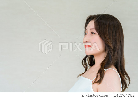 A woman in her 40s or 50s smiles and looks to the side. A beauty image with ample copy space. A woman in her 40s or 50s smiles and looks to the side. A beauty image with ample copy space. 142764792