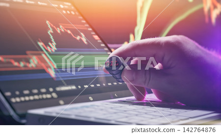 Crude oil commodity trading concept. Hand holding a miniature oil barrel in front of financial stock market charts on a laptop screen Crude oil commodity trading concept. Hand holding a miniature oil barrel in front of financial stock market charts on a laptop screen 142764876