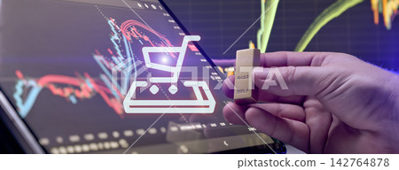 Online gold purchasing concept. Hand holding a gold bar with glowing shopping cart icon and financial trading charts Online gold purchasing concept. Hand holding a gold bar with glowing shopping cart icon and financial trading charts 142764878