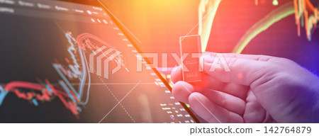 Gold commodity trading concept. Hand holding a gold bullion bar against digital financial stock market charts Gold commodity trading concept. Hand holding a gold bullion bar against digital financial stock market charts 142764879
