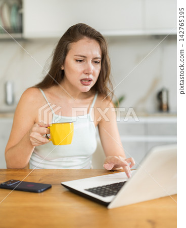 Woman working on a laptop in the kitchen Woman working on a laptop in the kitchen 142765195