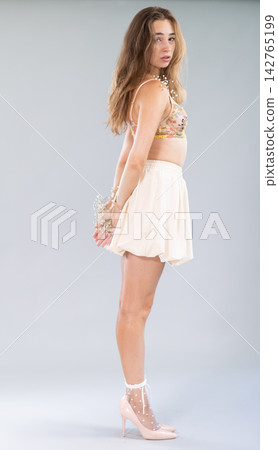 Sexy girl in a beige skirt and bra playfully poses in studio Sexy girl in a beige skirt and bra playfully poses in studio 142765199