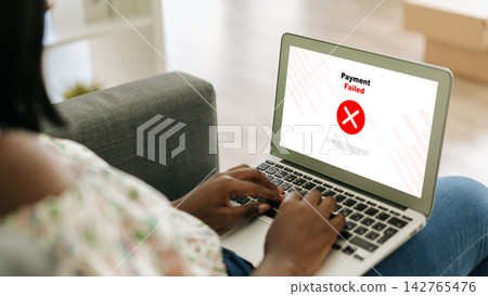 User sees payment failed message on laptop while sitting on sofa at home 142765476