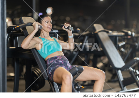 Athletic woman using shoulder press machine in gym Athletic woman using shoulder press machine in gym 142765477