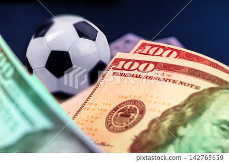 Sport betting with cash and a soccer ball in a casual setting during the day Sport betting with cash and a soccer ball in a casual setting during the day 142765659