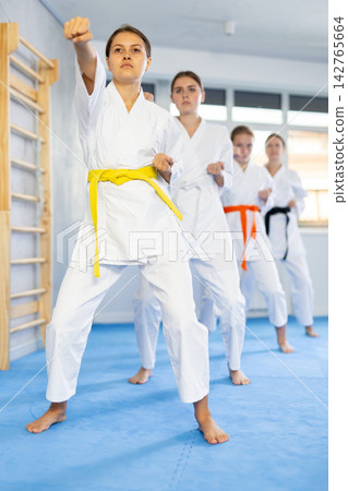 Adolescent karateka practicing punches during kata at group training Adolescent karateka practicing punches during kata at group training 142765664