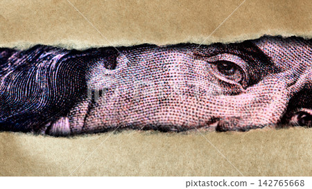 Dollar currency with a close-up view showing a face and details through torn paper Dollar currency with a close-up view showing a face and details through torn paper 142765668