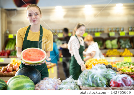 Grocery store saleswoman offers to buy ripe watermelon Grocery store saleswoman offers to buy ripe watermelon 142765669