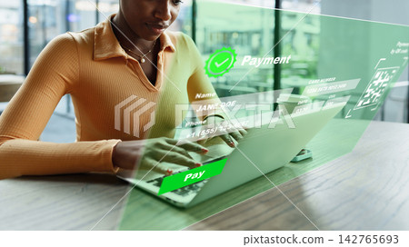 User makes an online payment using a laptop in a modern workspace during the day 142765693