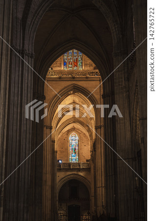 Sunlit gothic arches framing a distant gilded chapel in Seville Cathedral Sunlit gothic arches framing a distant gilded chapel in Seville Cathedral 142765722