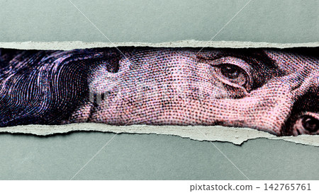 Details of a dollar bill showing a close-up of a prominent figure with parts of the bill visible through torn paper Details of a dollar bill showing a close-up of a prominent figure with parts of the bill visible through torn paper 142765761