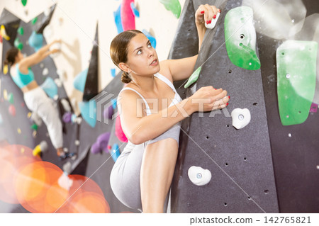 Young woman practicing rock climbing on climbing wall Young woman practicing rock climbing on climbing wall 142765821