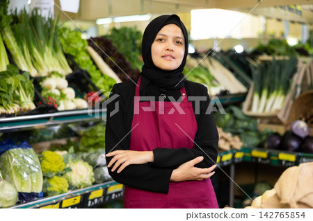 Muslim woman seller in hijab stands with arms crossed on chest and waits for customers 142765854